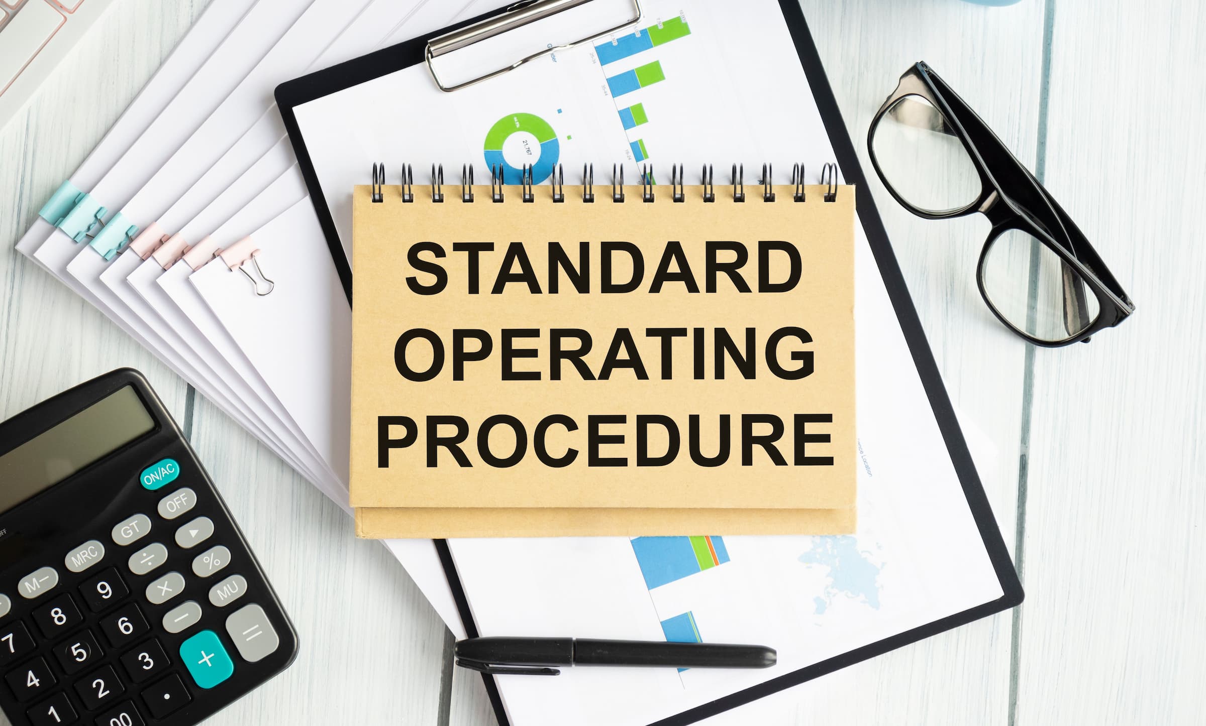 desk with various charts and a notebook titled Standard Operating Procedure