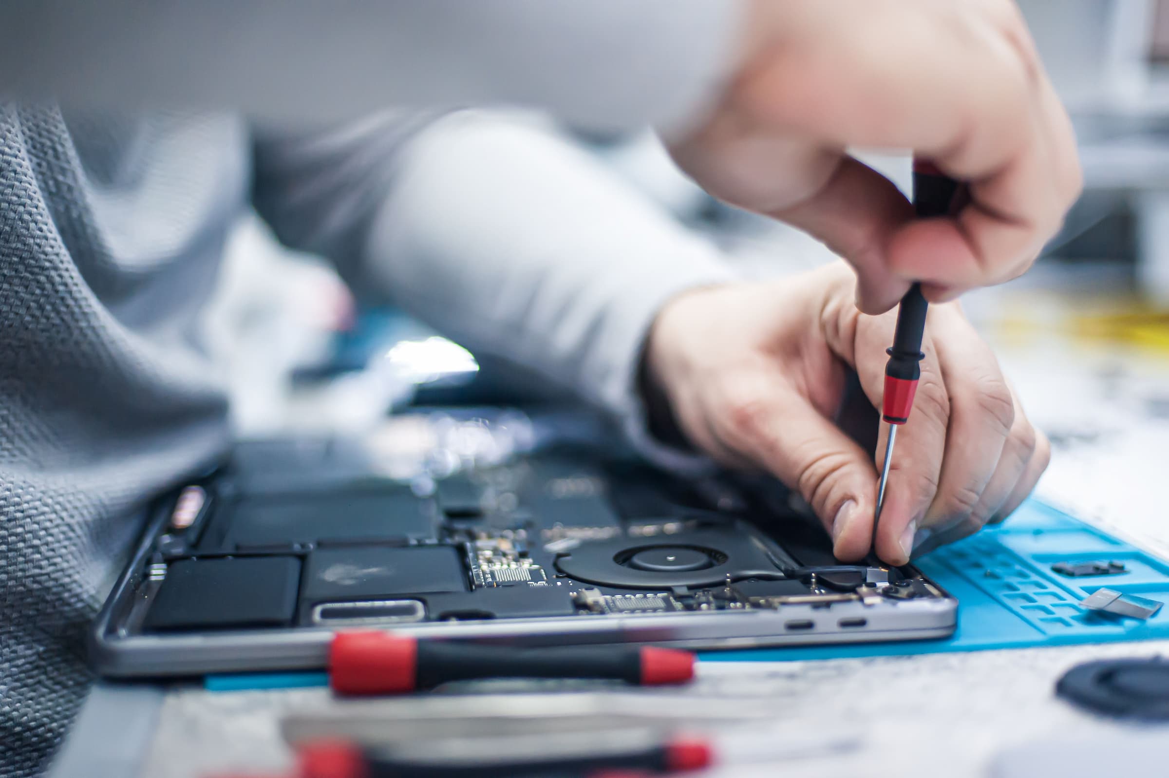 closeup of hands unscrewing electronic parts from computer