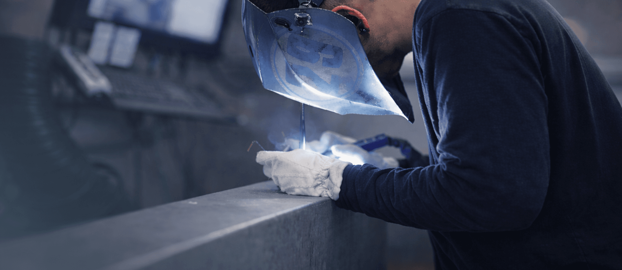 A worker welding with VKS on a computer