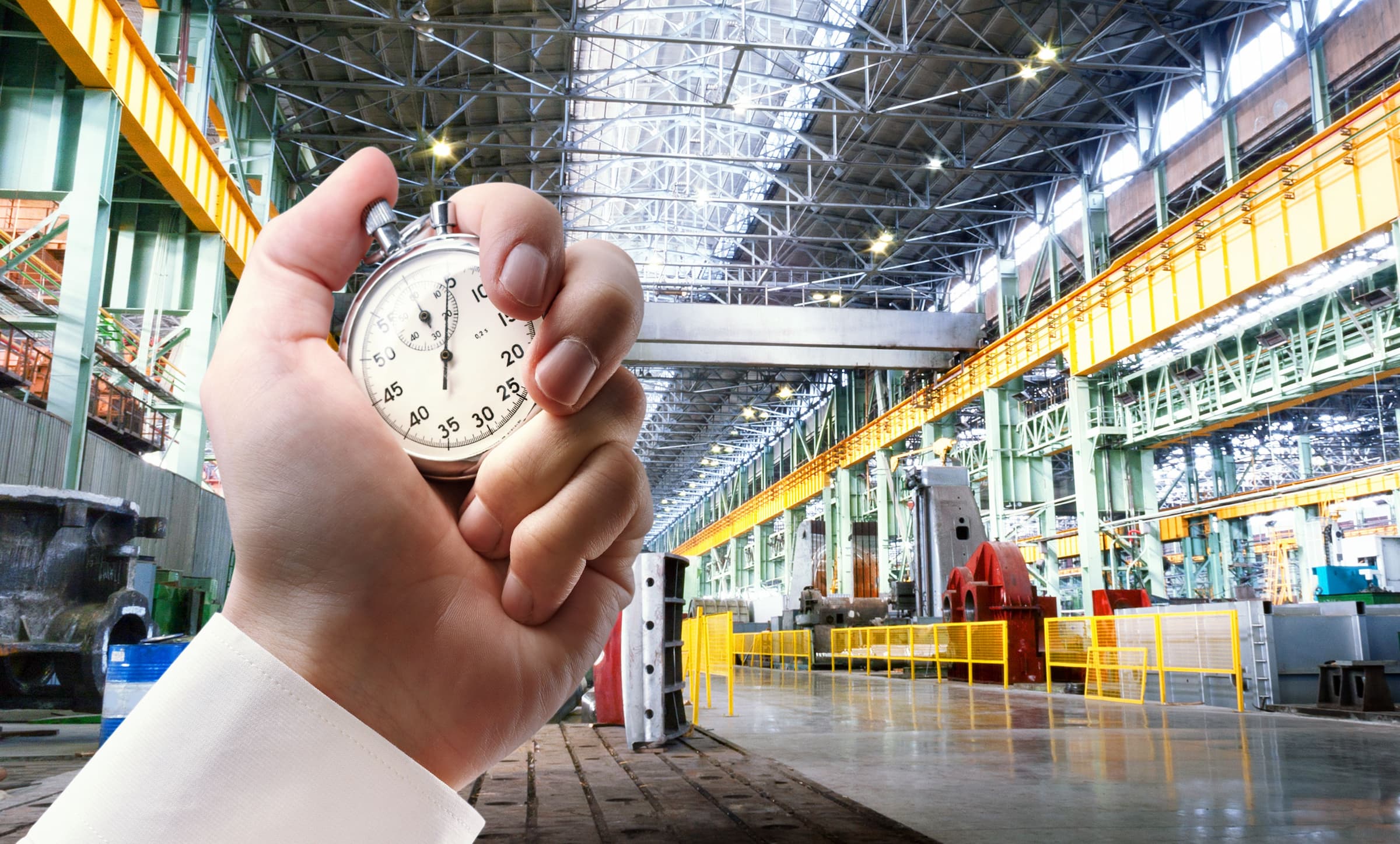 hand holds stopwatch in front of factory background