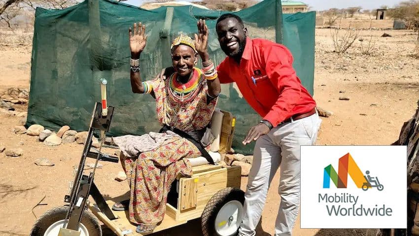 volunteer poses for picture with elderly woman using mobility cart